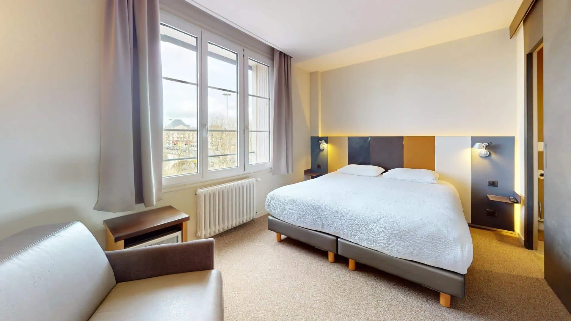 Chambre Double lumineuse de l'Hôtel de Harlay avec grand lit et fenêtres sur la ville