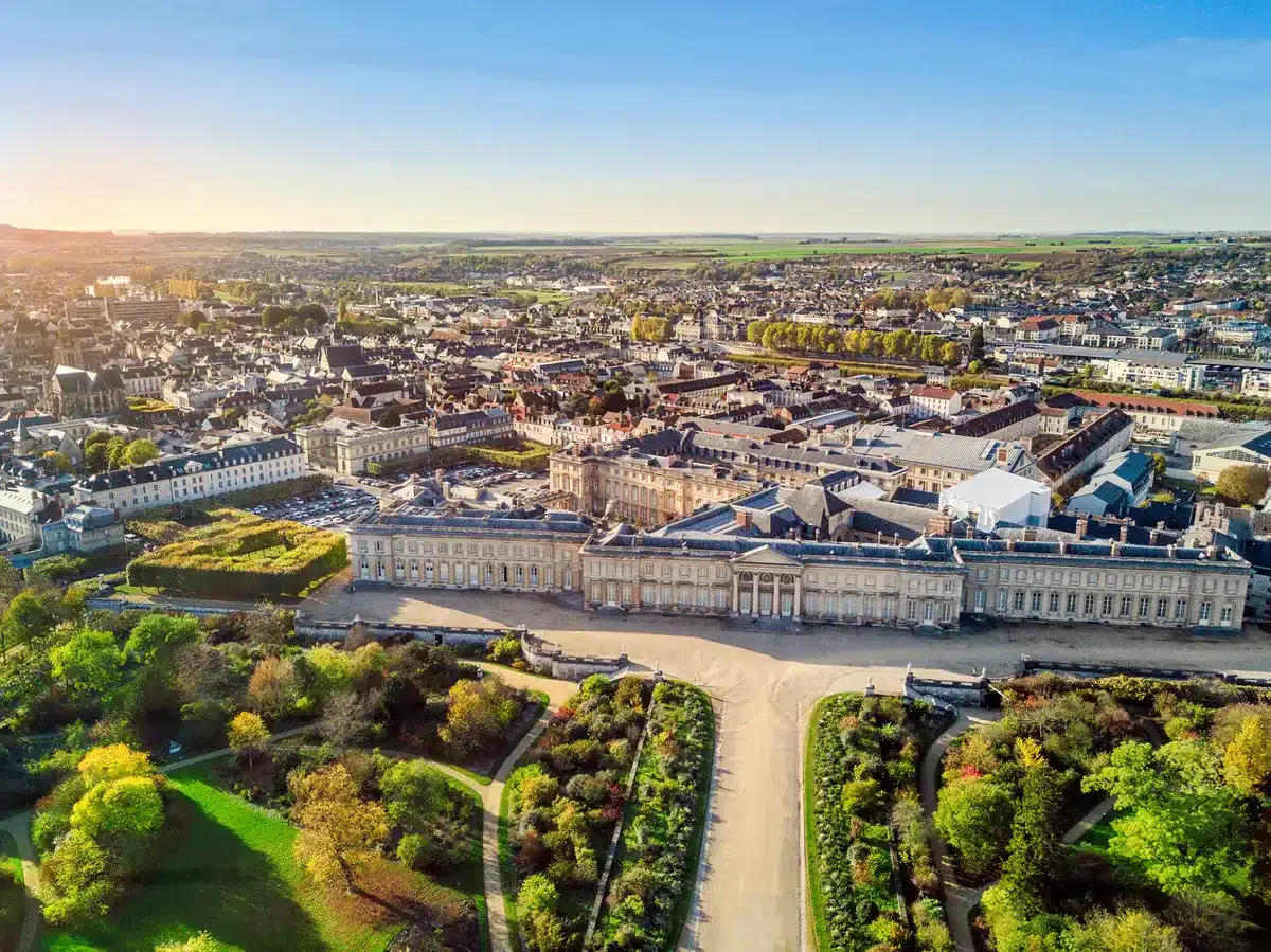 Vue aérienne du complexe historique de l'Hôtel de Harlay, entouré de jardins et de bâtiments urbains, sous un ciel bleu clair.